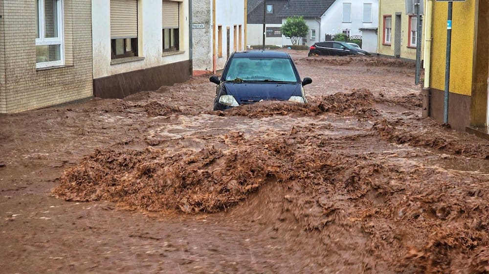 Ein Auto bahnt sich den Weg durch die Wassermassen. / Foto: Sebastian Schmitt/dpa