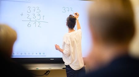 Eine Lehrerin schreibt eine Mathematikaufgabe auf eine digitale Schultafel. / Foto: Julian Stratenschulte/dpa