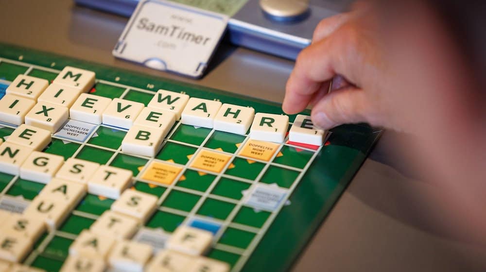 Ein Scrabble-Spieler sitzt an einem Spieltisch anlässlich der 14. Deutschen Scrabble-Meisterschaft in Minden und legt ein Wort in deutscher Sprache. / Foto: Friso Gentsch/dpa