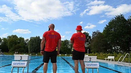 Zwei Sicherheitsmitarbeiter überblicken das Schwimmbecken. / Foto: Lars Penning/dpa/Archivbild