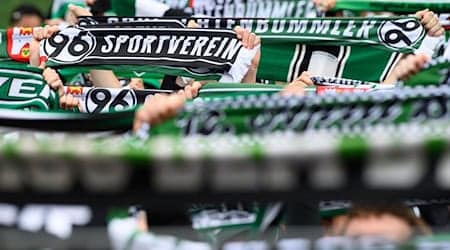 Hannovers Fans stehen mit ihren Schals auf der Tribüne. / Foto: Swen Pförtner/dpa
