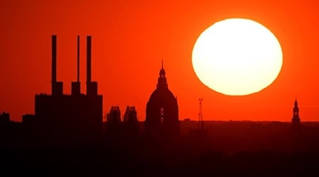 Die Sonne geht hinter dem Gaskraftwerk Linden und dem Neuen Rathaus unter. / Foto: Julian Stratenschulte/dpa