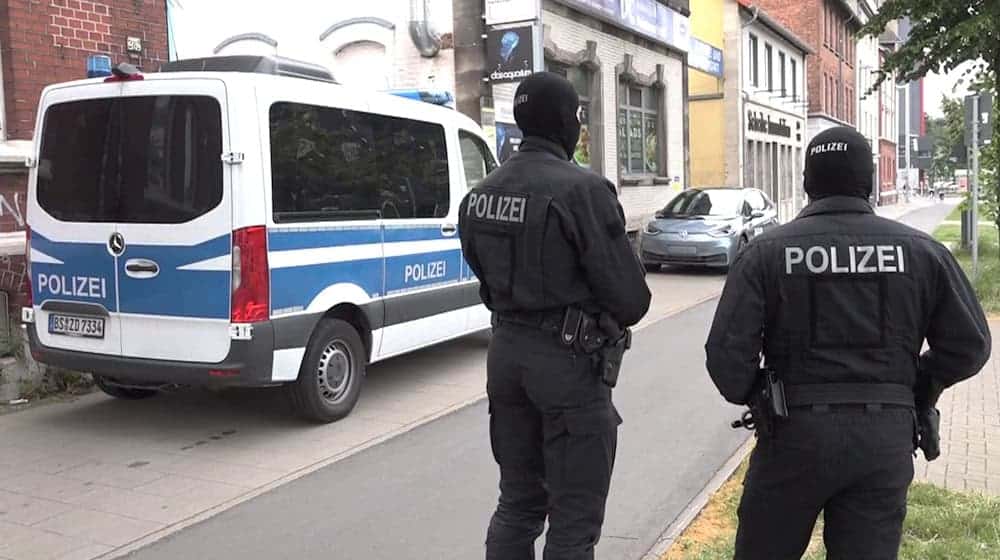 Polizeibeamte stehen vor einem der durchsuchten Objekte in Braunschweig. / Foto: dpa