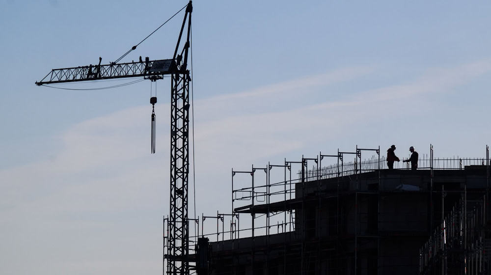 Bauarbeiter stehen auf der Baustelle eines Mehrfamilienhauses. / Foto: Julian Stratenschulte/dpa/Symbolbild