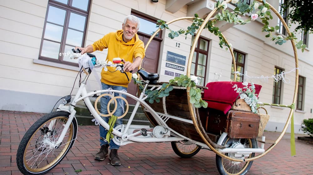 Metallkünstler Michael Olsen steht mit seinem Hochzeitsfahrrad vor dem Standesamt der Stadt Oldenburg am Pferdemarkt. / Foto: Hauke-Christian Dittrich/dpa