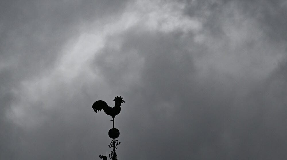 Über einem Wetterhahn schweben dunkle Regenwolken. / Foto: Bernd Weißbrod/dpa/Symbolbild
