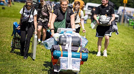 Festivalbesucher kommen mit ihrem Gepäck am Zeltplatz an. / Foto: Moritz Frankenberg/dpa