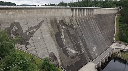 Auf der Staumauer der größten Trinkwassertalsperre Deutschlands wird mit Hochdruckreinigern ein Kunstwerk gemalt. / Foto: Matthias Bein/dpa