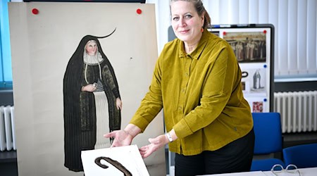 Annette Schieck, Leiterin des Deutschen Textilmuseums in Krefeld, zeigt bei der Präsentation bedeutender Textilfunde aus dem 16. und 17. Jahrhundert ein Horn aus Stoff. Es ist eine Besonderheit in Bremen. / Foto: Sina Schuldt/dpa