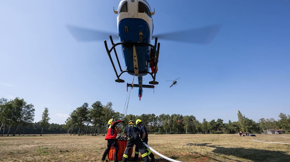 Geübt wurde unter anderem einen Behälter unter einem Helikopter im Schwebeflug mithilfe eines Füllrohrs mit Löschwasser zu füllen. / Foto: Philipp Schulze/dpa