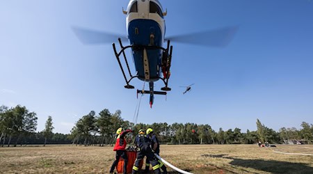 Geübt wurde unter anderem einen Behälter unter einem Helikopter im Schwebeflug mithilfe eines Füllrohrs mit Löschwasser zu füllen. / Foto: Philipp Schulze/dpa