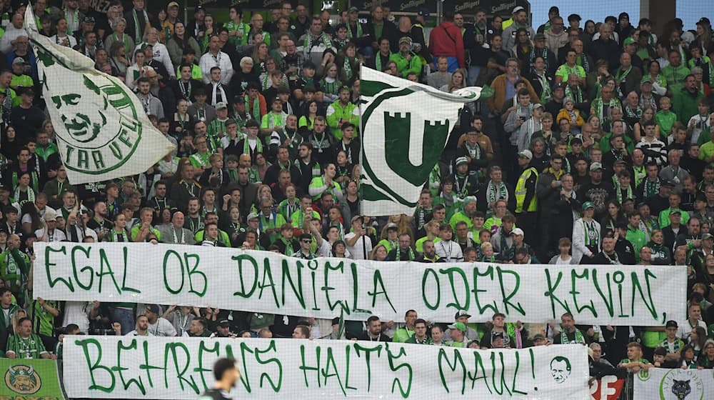 Wolfsburger Fans protestieren gegen Spieler Kevin Behrens und Niedersachsens Innenministerin Daniela Behrens. / Foto: Swen Pförtner/dpa