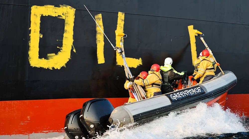 Aktivisten der Umweltorganisation Greenpeace malen den Schriftzug «Oil fuels war» auf den Rumpf eines Schiffes, das russisches Öl auf der Ostsee transportiert. (Archivbild) / Foto: Frank Molter/dpa