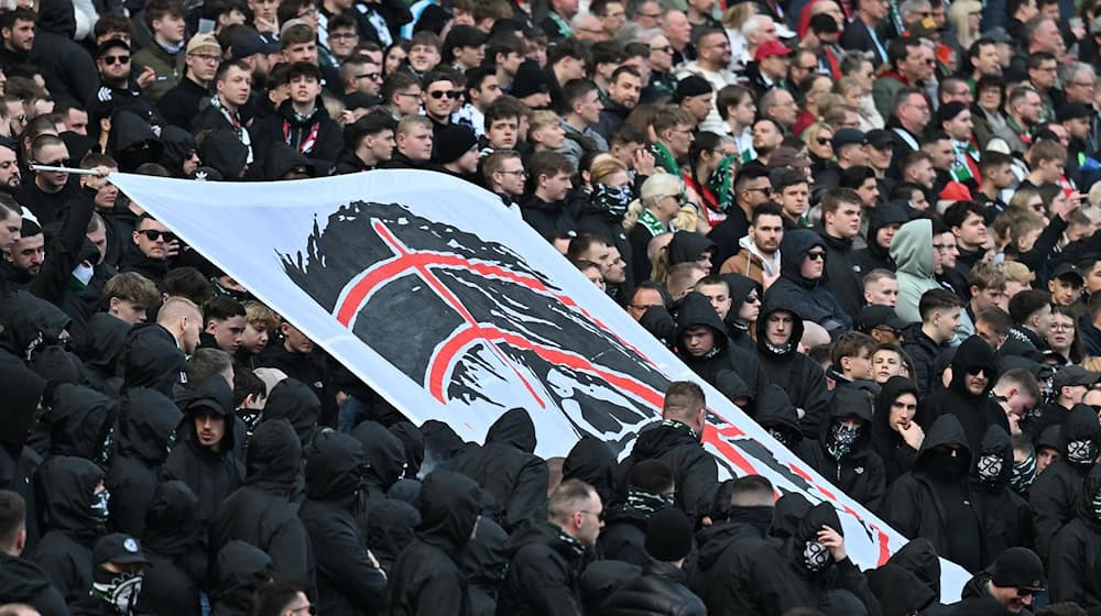 Hannover-Fans halten auf der Tribüne ein Plakat hoch, dass den Kopf von Niedersachsens Innenministerin Daniela Behrens in einem Fadenkreuz zeigt. / Foto: Swen Pförtner/dpa