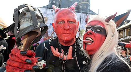Im Teufelskostüm stehen Besucher auf dem Marktplatz in Wernigerode.  / Foto: Matthias Bein/dpa