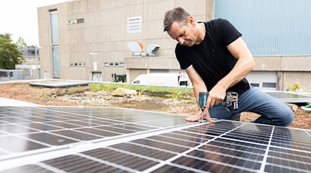 Olaf Lies, damals noch als Wirtschaftsminister, montiert ein Solarmodul auf ein Dach. (Archivbild) / Foto: Michael Matthey/dpa