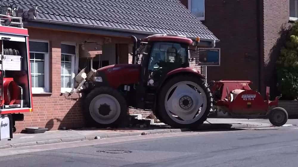 Ein Traktor steckt in einer stark beschädigten Hauswand. Wich der Fahrer einem Schulbus aus?  / Foto: Benjamin Müller/TNN/dpa