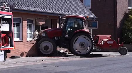 Ein Traktor steckt in einer stark beschädigten Hauswand. Wich der Fahrer einem Schulbus aus?  / Foto: Benjamin Müller/TNN/dpa