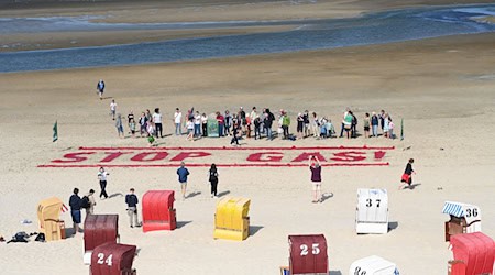Klimaschutzaktivisten von Fridays for Future schreiben ihre Forderung nach einem Ende der Gasförderung auf den Strand der Insel Borkum.  / Foto: Lars Penning/dpa
