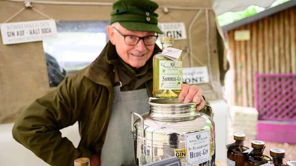 Gerhard Bosselmann zeigt seinen Sommer-Gin, der unter anderem aus Heidekrautblüten besteht.  / Foto: Philipp Schulze/dpa