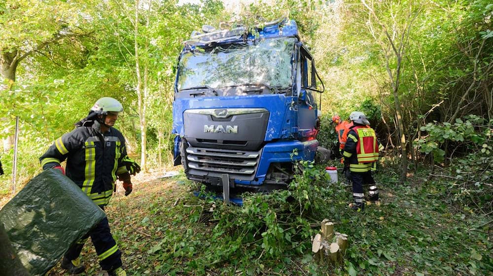 Einsatzkräfte der Feuerwehr stehen neben dem verunfallten Lkw an der Bundesstraße B3. / Foto: Julian Stratenschulte/dpa