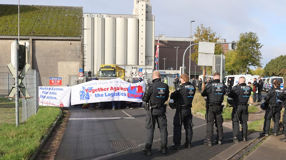 Mit einer Sitzblockade protestieren Aktivisten vor der Zufahrt eines Hafendienstleisters in Bremen-Walle.  / Foto: Christian Butt/dpa