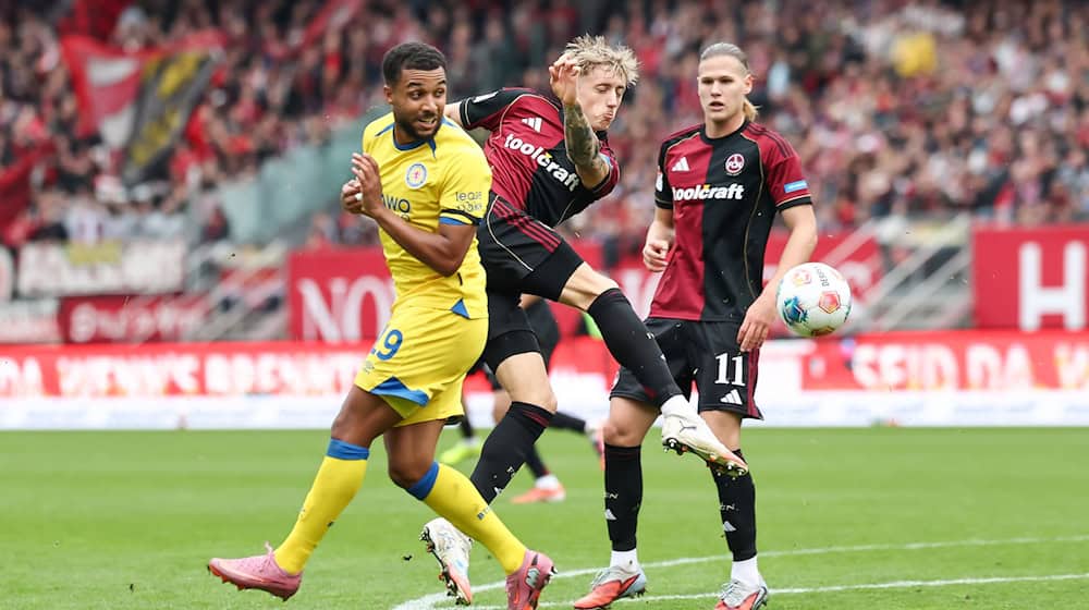In Aktion: Tim Drexler vom 1. FC Nürnberg (M) und Leon Bell-Bell von Eintracht Braunschweig. / Foto: Daniel Löb/dpa