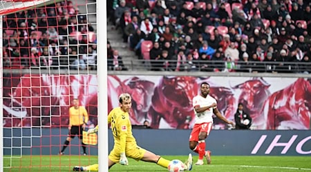 Bremens Torwart Mio Backhaus (l, Werder Bremen) und Ridle Baku (RB Leipzig) schauen dem Ball hinterher. Backhaus verhinderte mit seinen Paraden einen frühen Rückstand der Gäste in Leipzig. / Foto: Jennifer Brückner/dpa