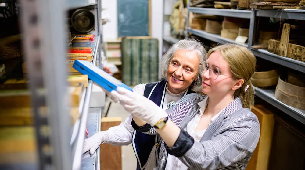 Christine Strüfing (l), ehemalige Lehrerin, und Lea Finzel, Kuratorin, schauen sich im Kiekeberg-Museum verschiedene Exponate an. Christine Strüfing trug tausende Objekte aus der Schule zusammen. / Foto: Philipp Schulze/dpa
