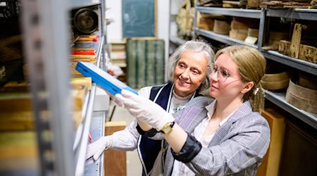 Christine Strüfing (l), ehemalige Lehrerin, und Lea Finzel, Kuratorin, schauen sich im Kiekeberg-Museum verschiedene Exponate an. Christine Strüfing trug tausende Objekte aus der Schule zusammen. / Foto: Philipp Schulze/dpa