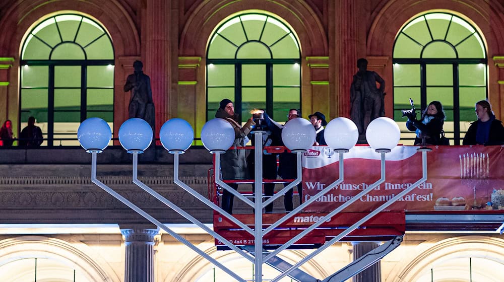 Das erste Licht am Leuchter wird entzündet. / Foto: Moritz Frankenberg/dpa