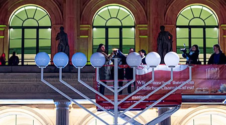 Das erste Licht am Leuchter wird entzündet. / Foto: Moritz Frankenberg/dpa