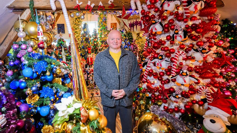 Thomas Jeromin steht inmitten von Weihnachtsbäumen in seinem Haus im Landkreis Schaumburg.  / Foto: Julian Stratenschulte/dpa