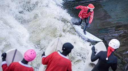 Beim «Santa Surf» stürzen sich verkleidete Surfer in die eiskalte Leinewelle in Hannover. / Foto: Moritz Frankenberg/dpa