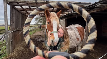 Sophie Dongowski zeigt neben ihrem Pferd Valentino ein aus Pferdehaar und Menschenhaar gefertigtes Armband.  / Foto: Julian Stratenschulte/dpa