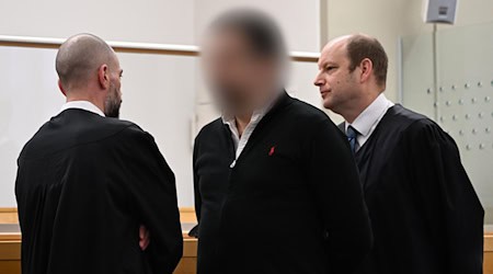 Der angeklagte Staatsanwalt aus Hannover hat gestanden, gegen Geld eine international agierende Kokain-Bande mit Informationen versorgt zu haben. Im Hintergrund sind seine zwei Verteidiger im Gespräch zu sehen. / Foto: Shireen Broszies/dpa