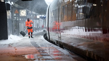 Mitarbeiter schieben Schnee von einem Bahnsteig am Hamburger Hauptbahnhof. / Foto: Christian Charisius/dpa