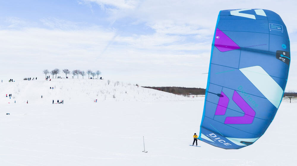 Ein Kite-Surfer gleitet am Kronsberg mit seinem Board über den Schnee. / Foto: Julian Stratenschulte/dpa
