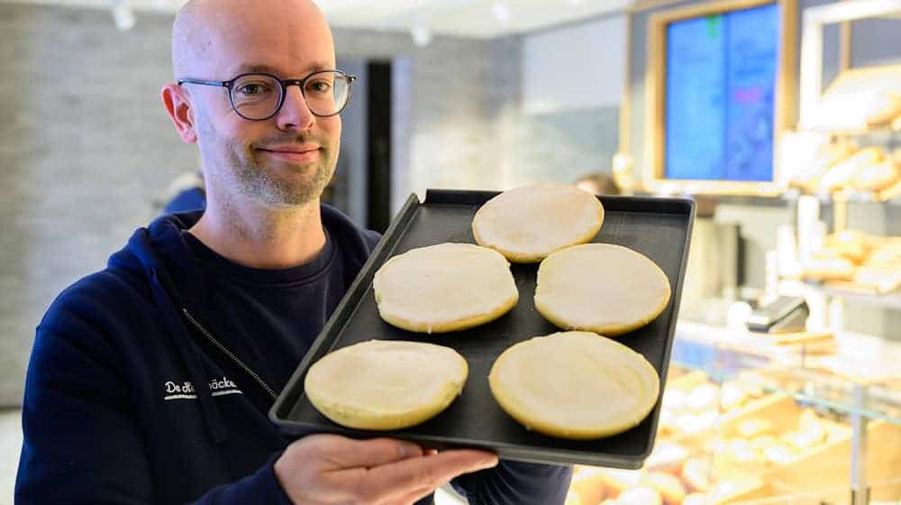 Jannik Harms, Geschäftsführer der De Heidbäcker GmbH, hält ein Blech «Grönländer» in der Hand. / Foto: Philipp Schulze/dpa