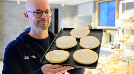 Jannik Harms, Geschäftsführer der De Heidbäcker GmbH, hält ein Blech «Grönländer» in der Hand. / Foto: Philipp Schulze/dpa