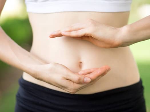 Frau hält schützend die Hände vor ihren Bauch als Symbol für Darmgesundheit und Verdauung
