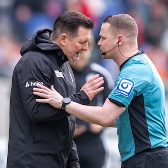 96-Trainer Christian Titz (l) spricht mit Schiedsrichter Robert Kampka. / Foto: David Inderlied/dpa