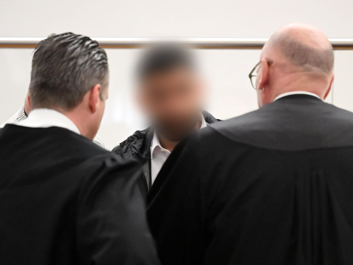 Der Angeklagte (M) spricht im Gerichtssaal mit zwei Strafverteidigern. Zu Prozessbeginn sind weiterhin viele Fragen offen. / Foto: Shireen Broszies/dpa