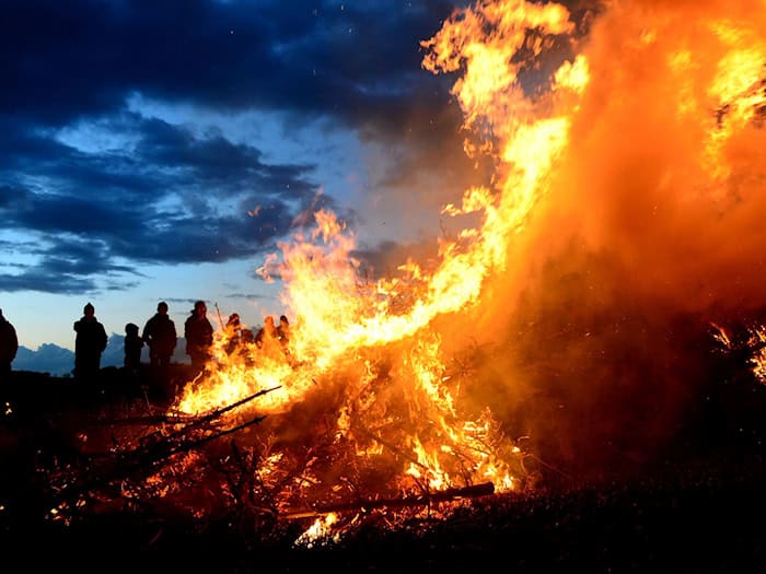 Ein Osterfeuer lodert in der Dämmerung: Der traditionelle Brauch steht zwischen geselligem Frühlingsevent und der Kritik von Natur- und Tierschützern. (Symbolbild) / Foto: Maurizio Gambarini/dpa