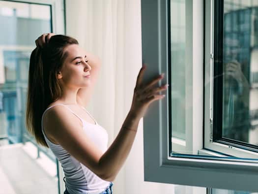Frau öffnet Fenster und lüftet