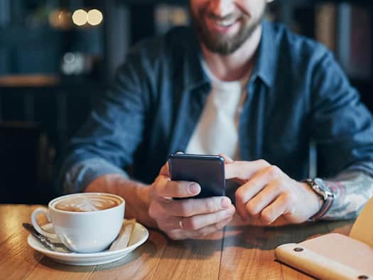 Mann spielt im Café auf Smartphone im legalen Online-Casino