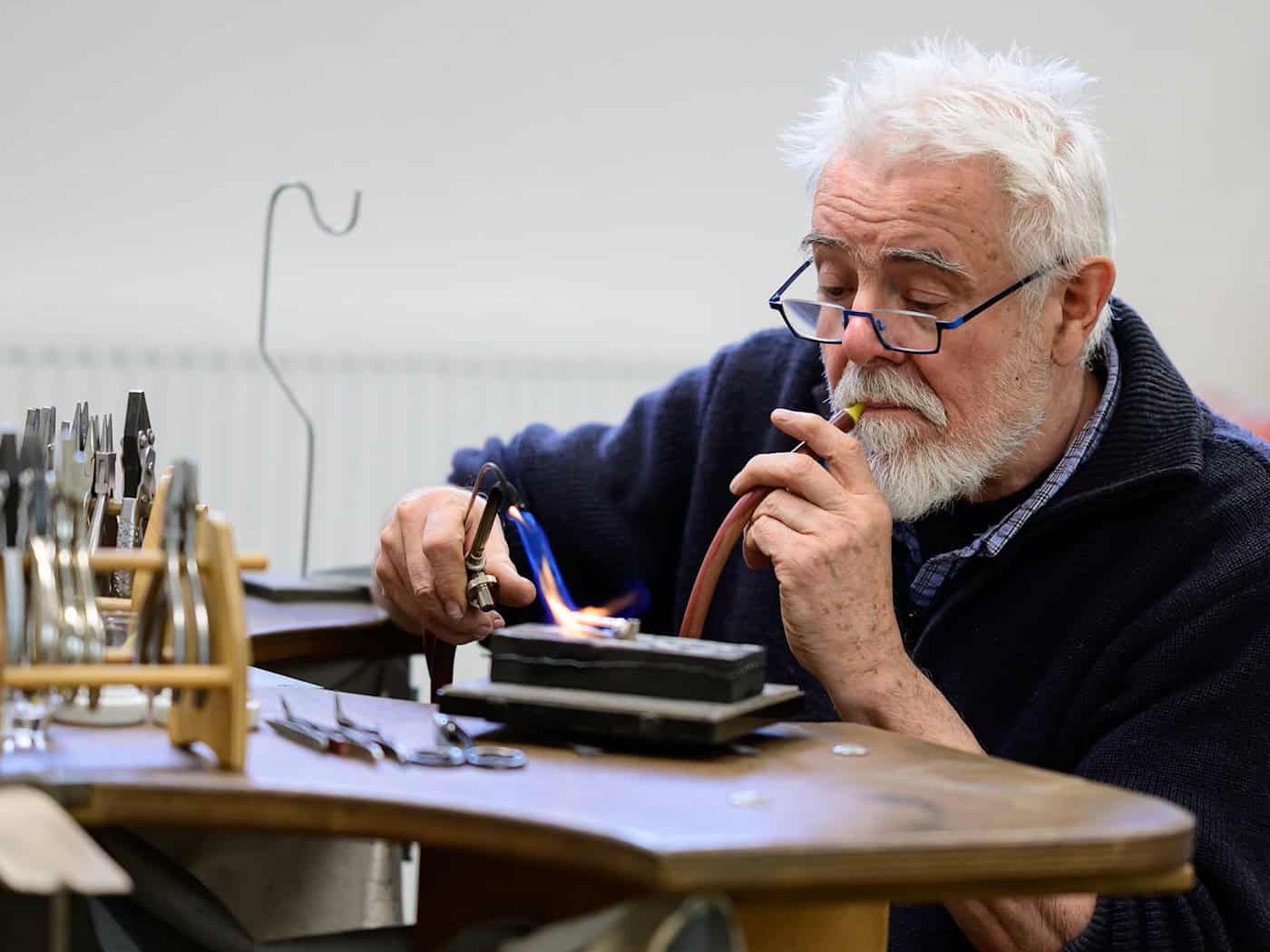 Goldschmied Peter Reddersen arbeitet seit mehr als 40 Jahren in seiner Werkstatt auf dem Werkhof Kukate.  / Foto: Philipp Schulze/dpa