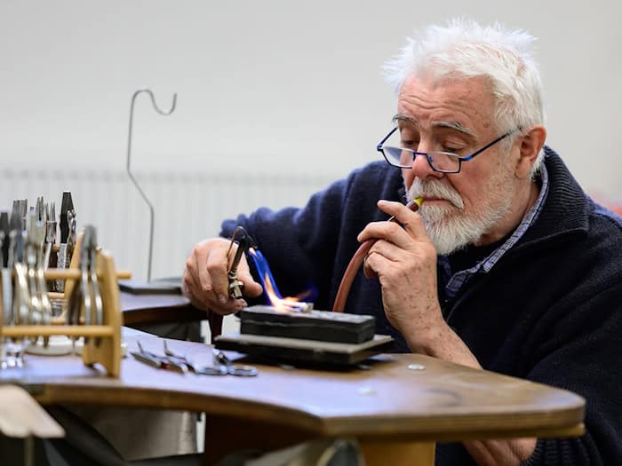 Goldschmied Peter Reddersen arbeitet seit mehr als 40 Jahren in seiner Werkstatt auf dem Werkhof Kukate.  / Foto: Philipp Schulze/dpa
