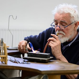 Goldschmied Peter Reddersen arbeitet seit mehr als 40 Jahren in seiner Werkstatt auf dem Werkhof Kukate.  / Foto: Philipp Schulze/dpa