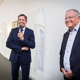 Ministerpräsident Olaf Lies (SPD, links) und dessen direkter Vorgänger Stephan Weil (auch SPD) stehen vor der Enthüllung des Porträts von Weil in der Niedersächsischen Staatskanzlei. / Foto: Moritz Frankenberg/dpa